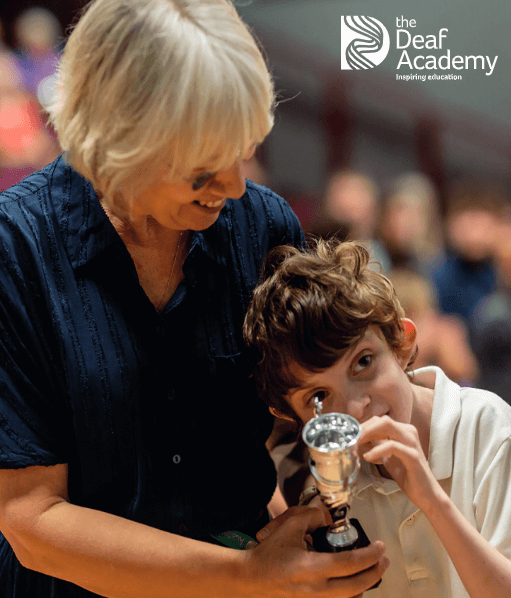 Teacher with a young student with a cup for winning an award