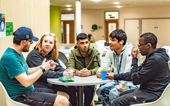5 students around the table chatting