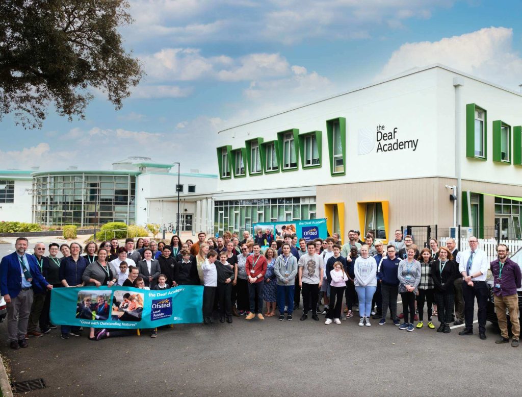 Students and staff outside the Deaf Academy building showing the Ofsted Good Provider banner for school and college sixth form